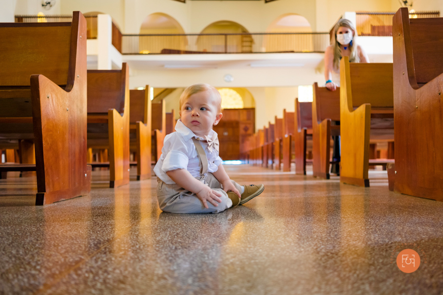 menino sentado no corredor da igreja batizado