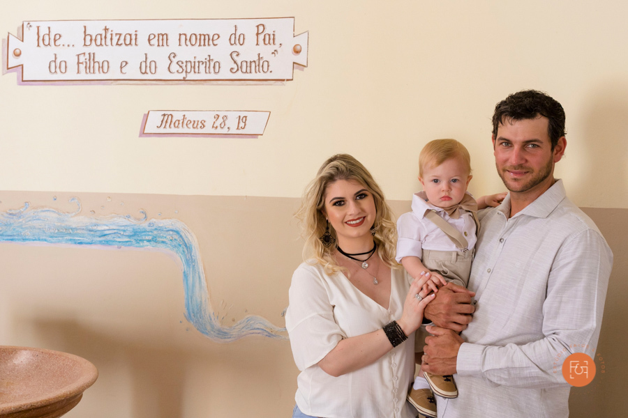 menino com os pais no batizado