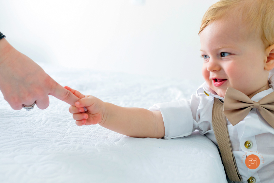 menino pegando na mão na mãe batizado