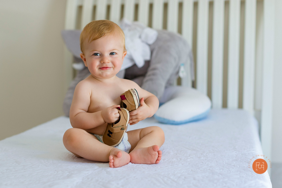 menino brincando na cama com sapatinhos na mão