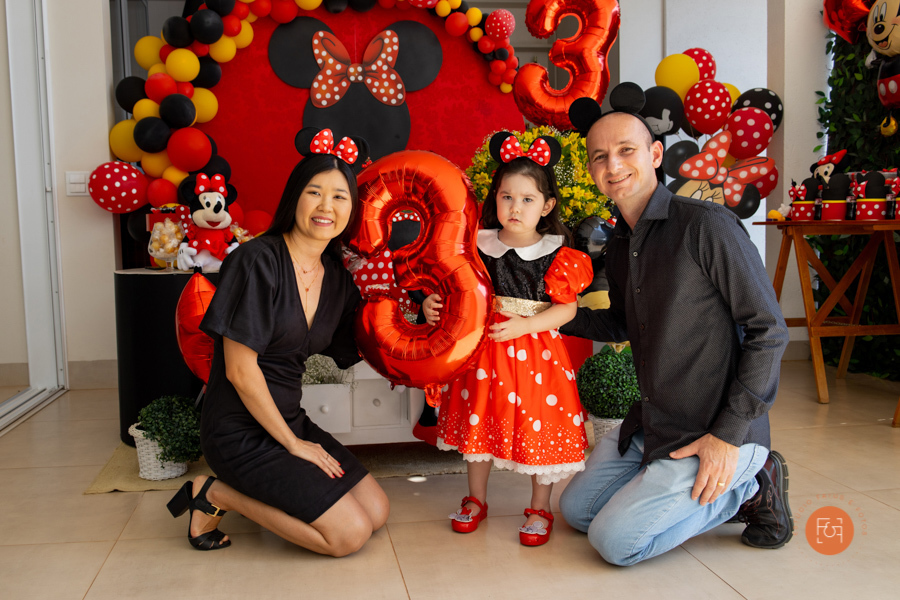 aniversariante menina segurando um balão de número 3 com os pais