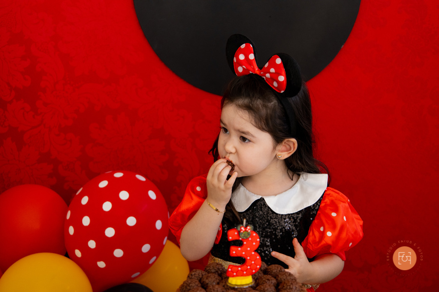 aniversariante menina na mesa do bolo comendo brigadeiro
