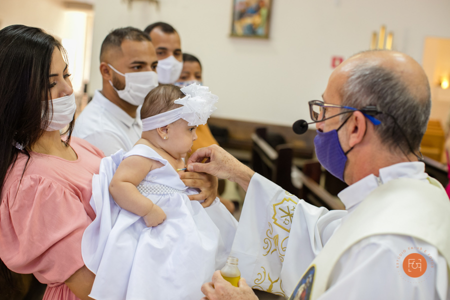 bebe recebendo a benção do padre no batizado