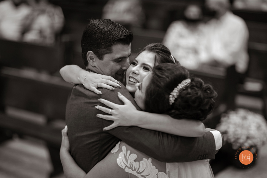 noivo e noiva abraçando a filha no altar