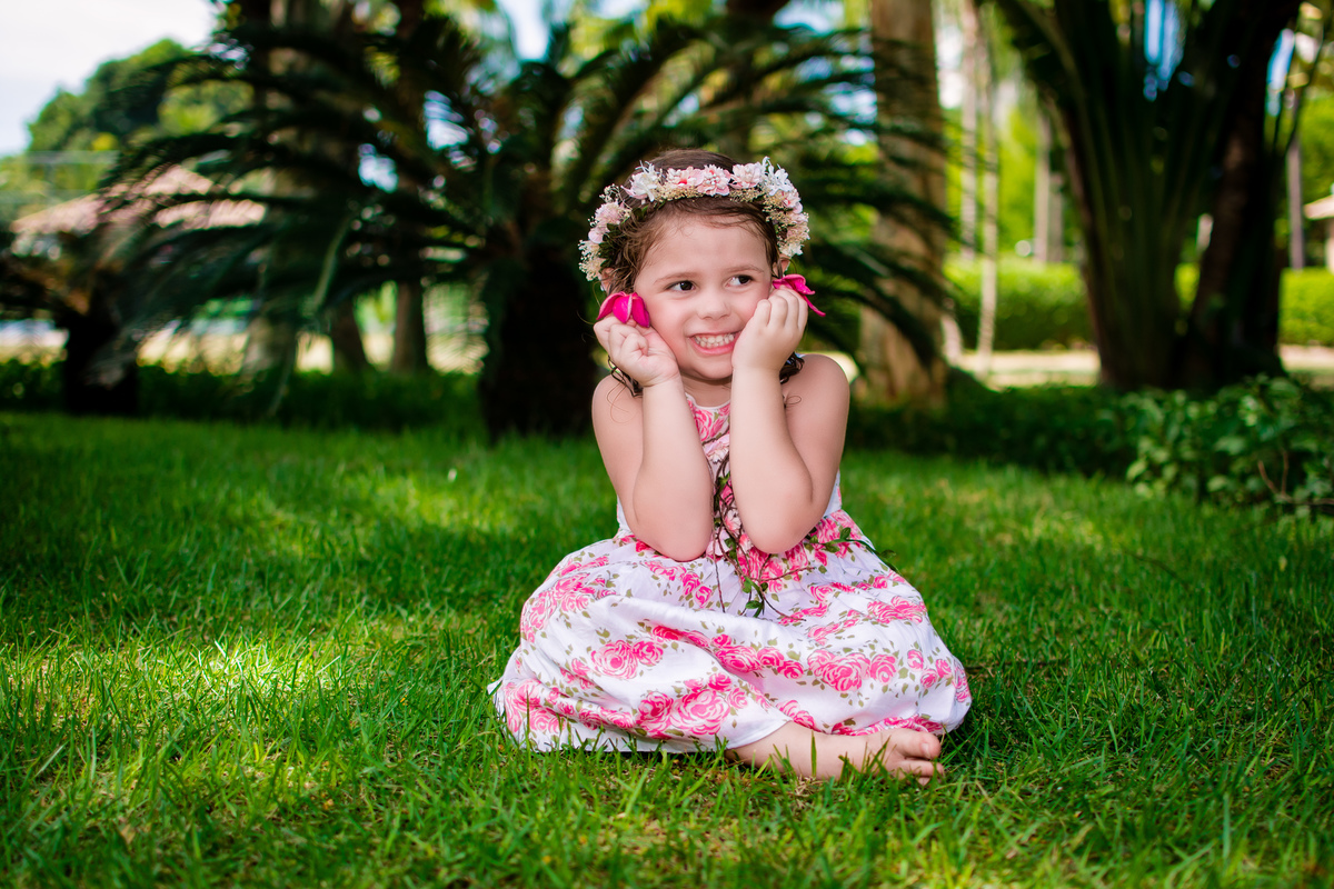 Carol de vestido branco estampado com flores rosa no gramado do Rio 2 Park na Barra da Tijuca\RJ, ensaio fotográfico infantil pirralhitus.