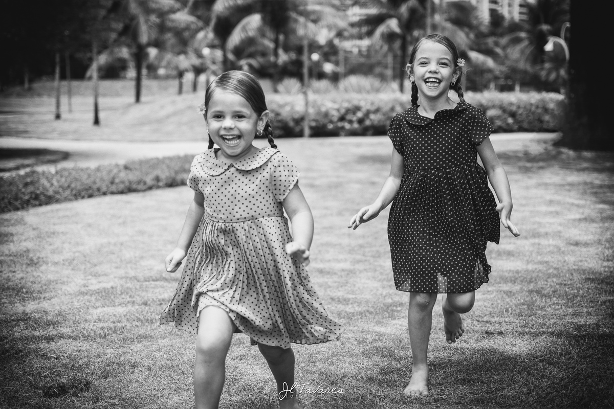 foto de duas crianças correndo no gramado durante ensaio fotográfico infantil