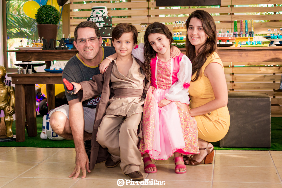 familia reunida na frente da mesa do bolo, crianças fantasiadas de Luke Skywallker e Cinderela