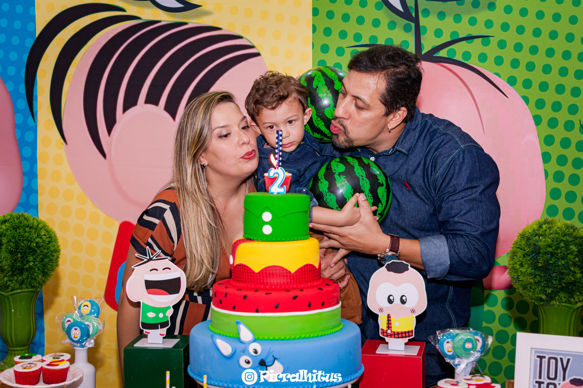 Arthur e seus pais assoprando a vela do bolo.