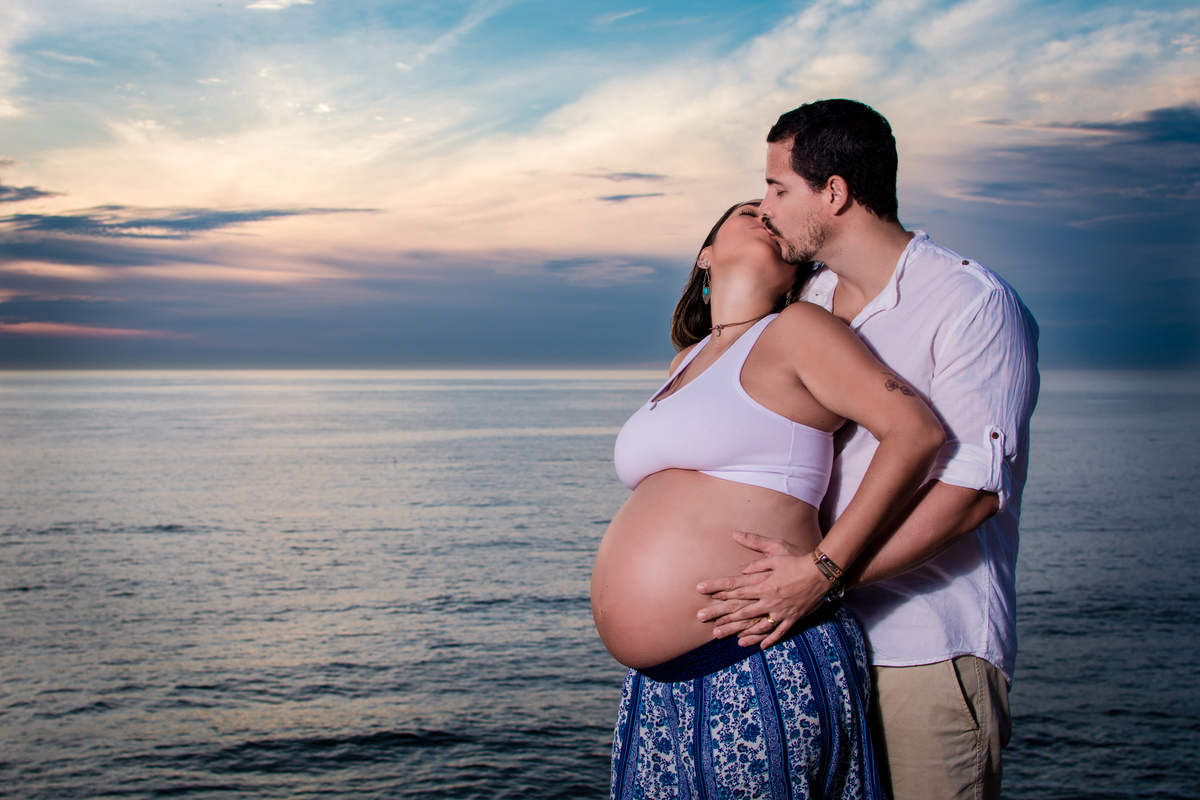 Casal durante ensaio fotográfico gestante na Praia de Grumari com o sol nascendo.