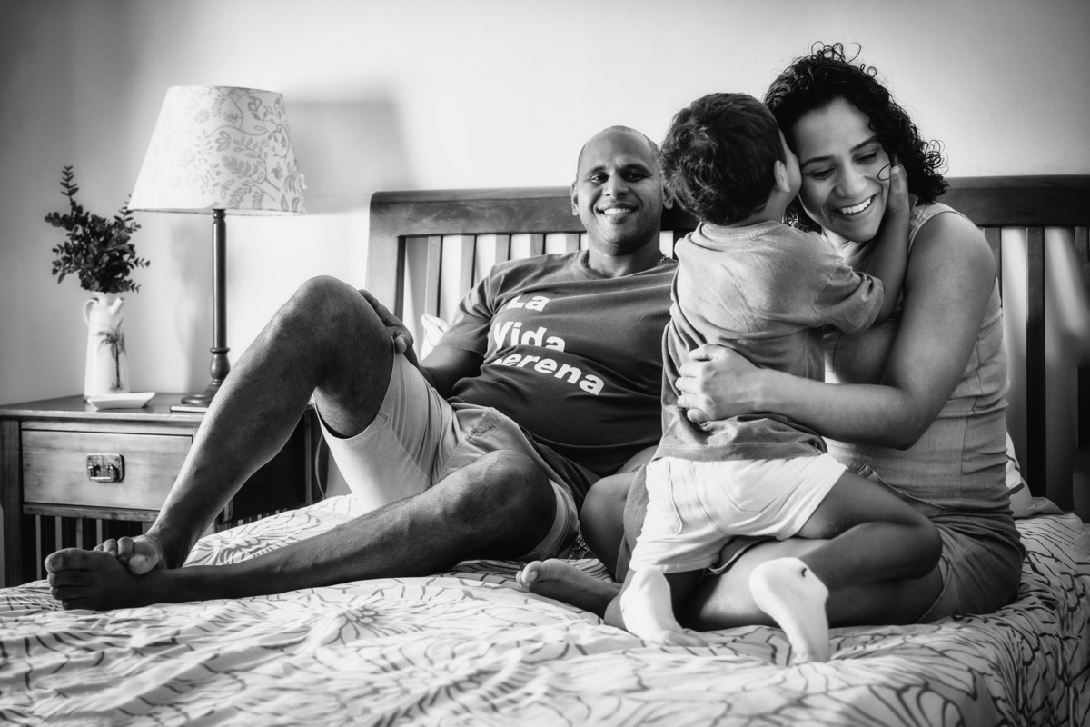 Filho contando segredo para a mãe grávida em cima da cama.