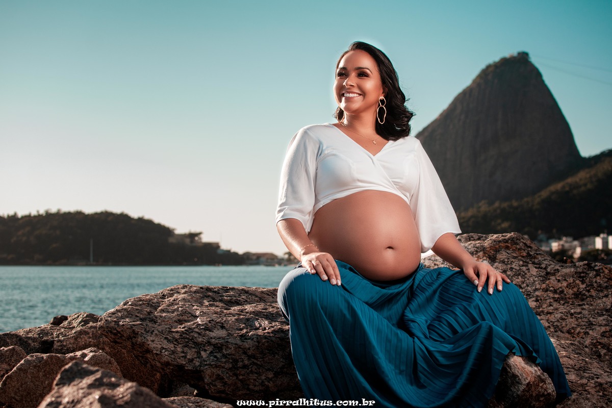 Linda gestante usando bata branca e saia azul tifany no aterro do flamengo.