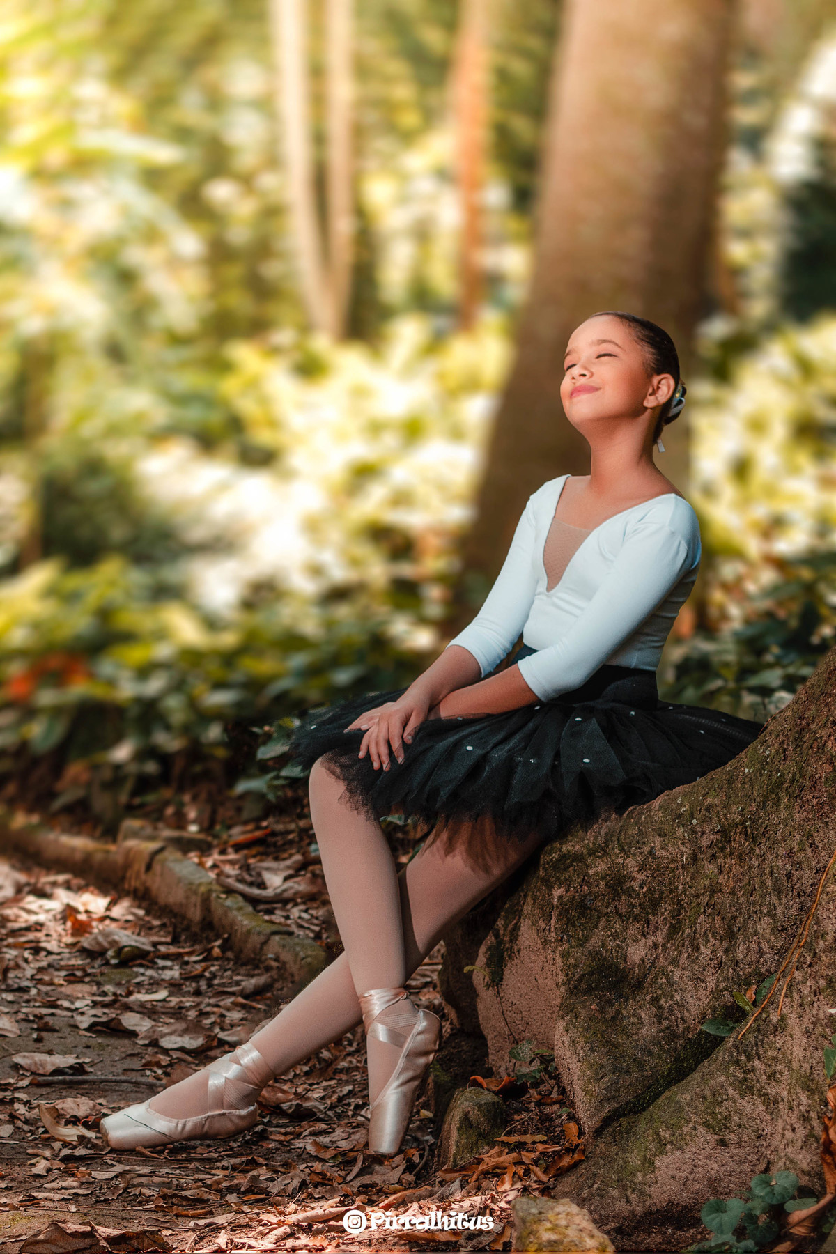 Menina bailarina sentada ao pé de uma uma árvore no Parque Laje. Collant Branco e Tutu Preto.