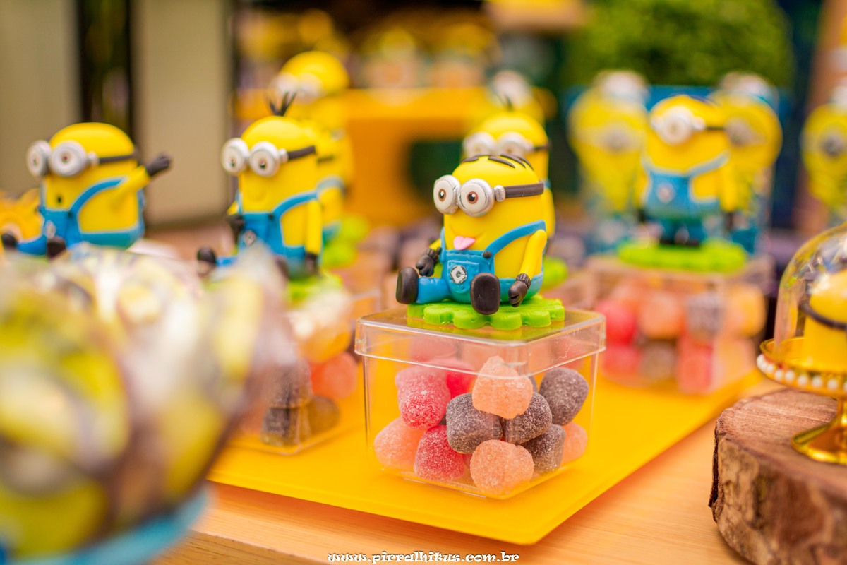 Fotografia de detalhe da decoração da mesa do bolo. Caixinha de jujuba com minion de biscuit Casa de festas Espaço Animania.