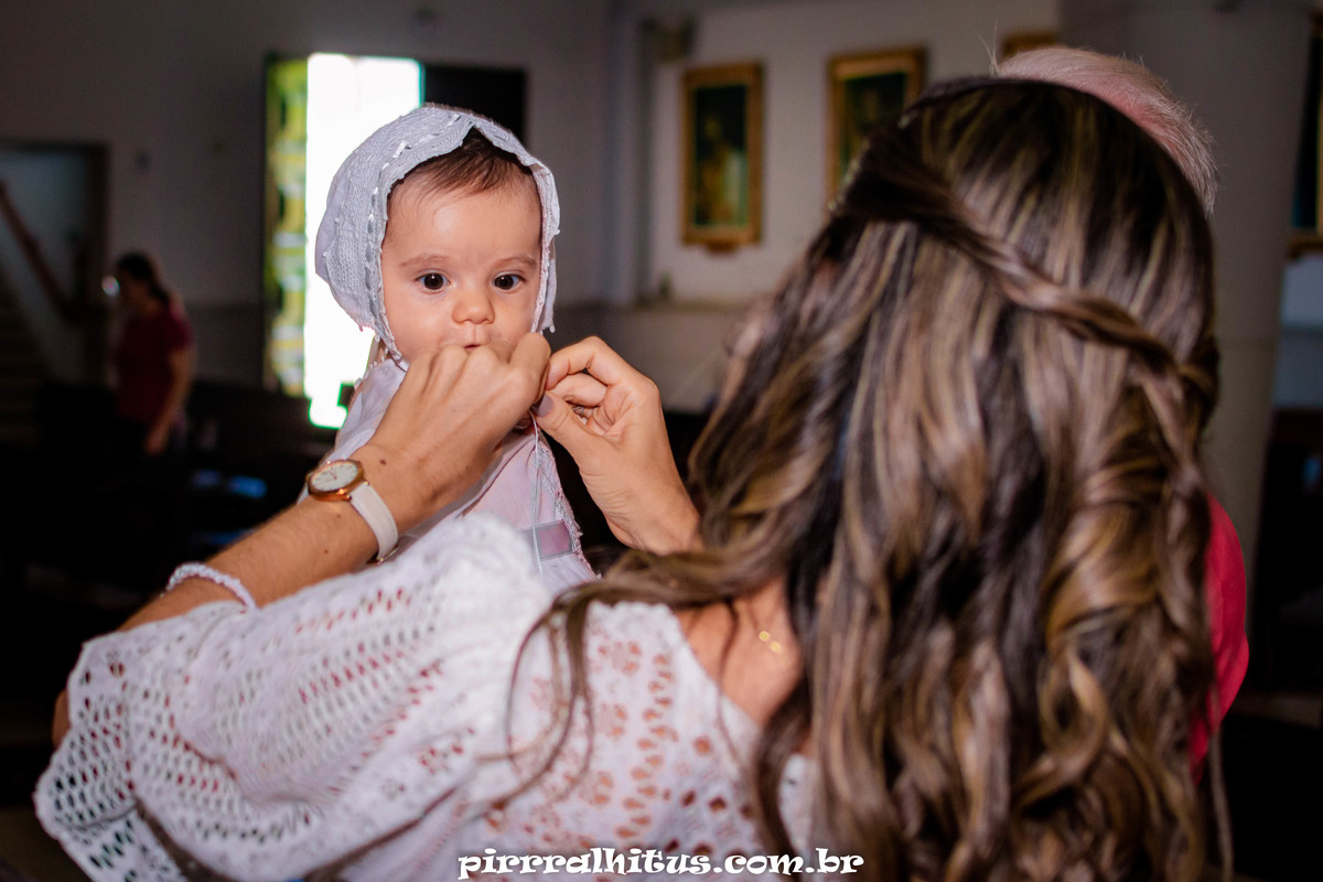 Mãe arrumando a touquinha de batismo da bebê;