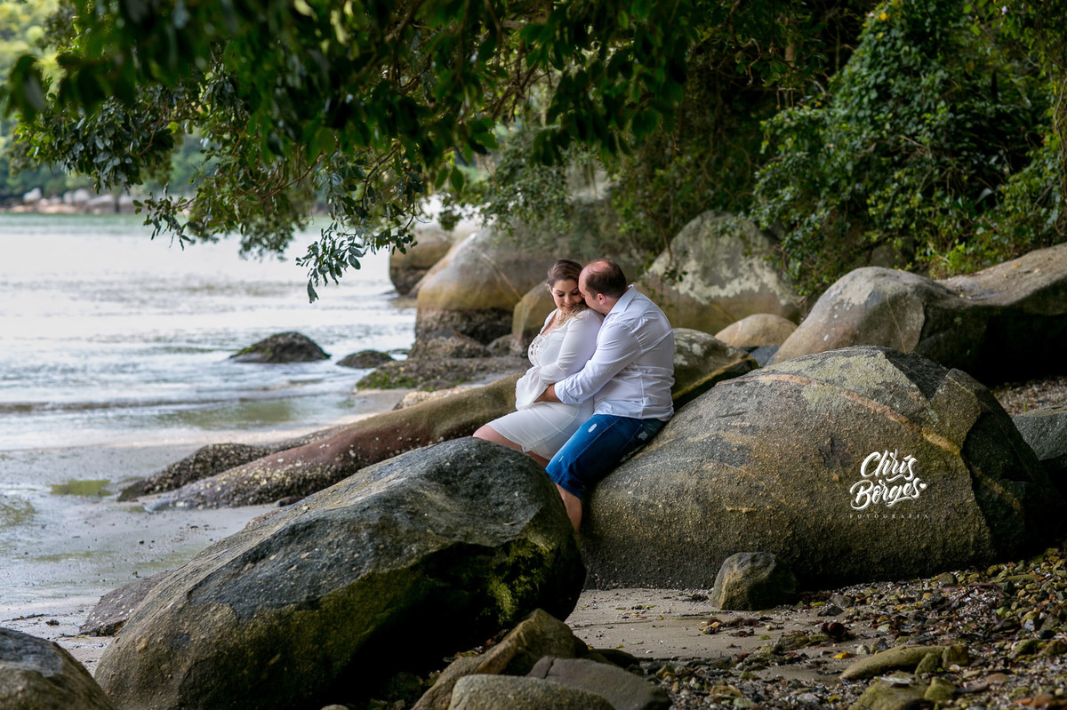 noivos sentados na beira do mar