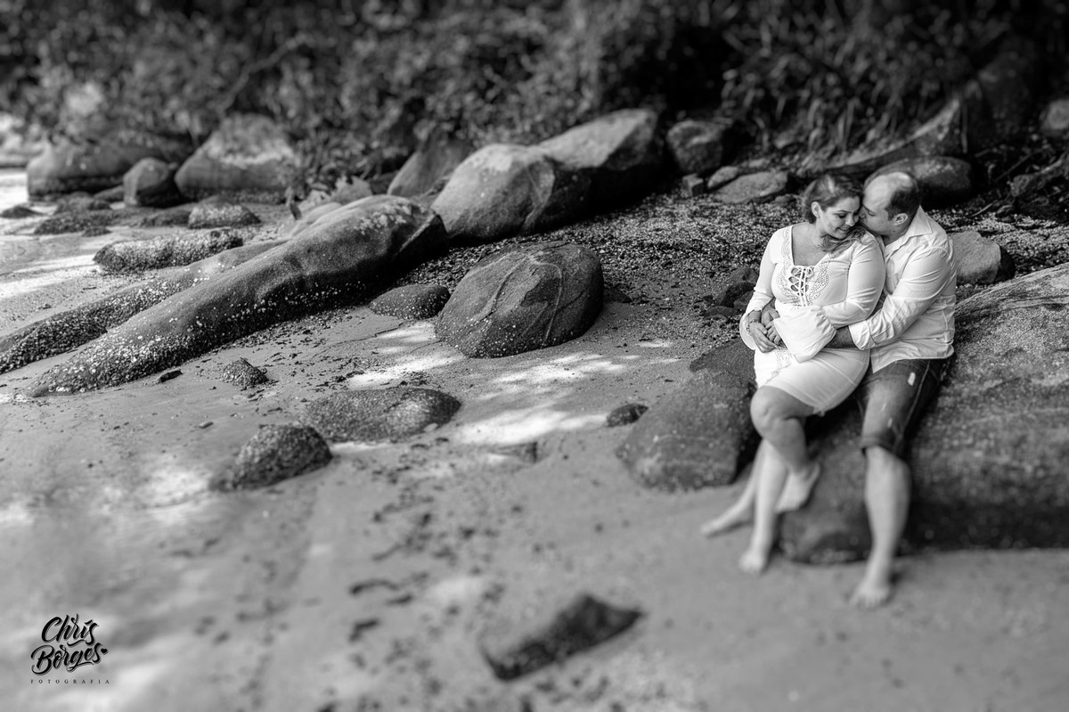 noivos sentados na beira do mar