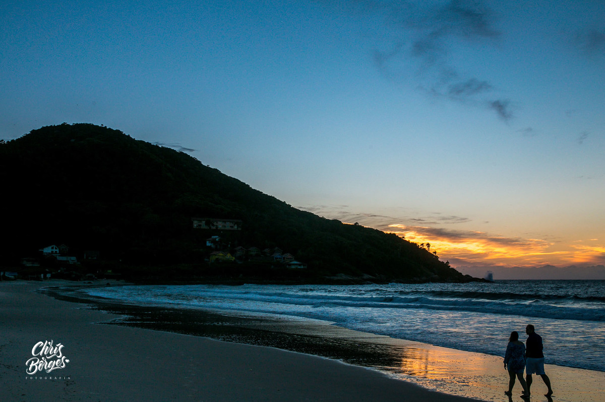 Noivos passeando na praia ao nascer do sol