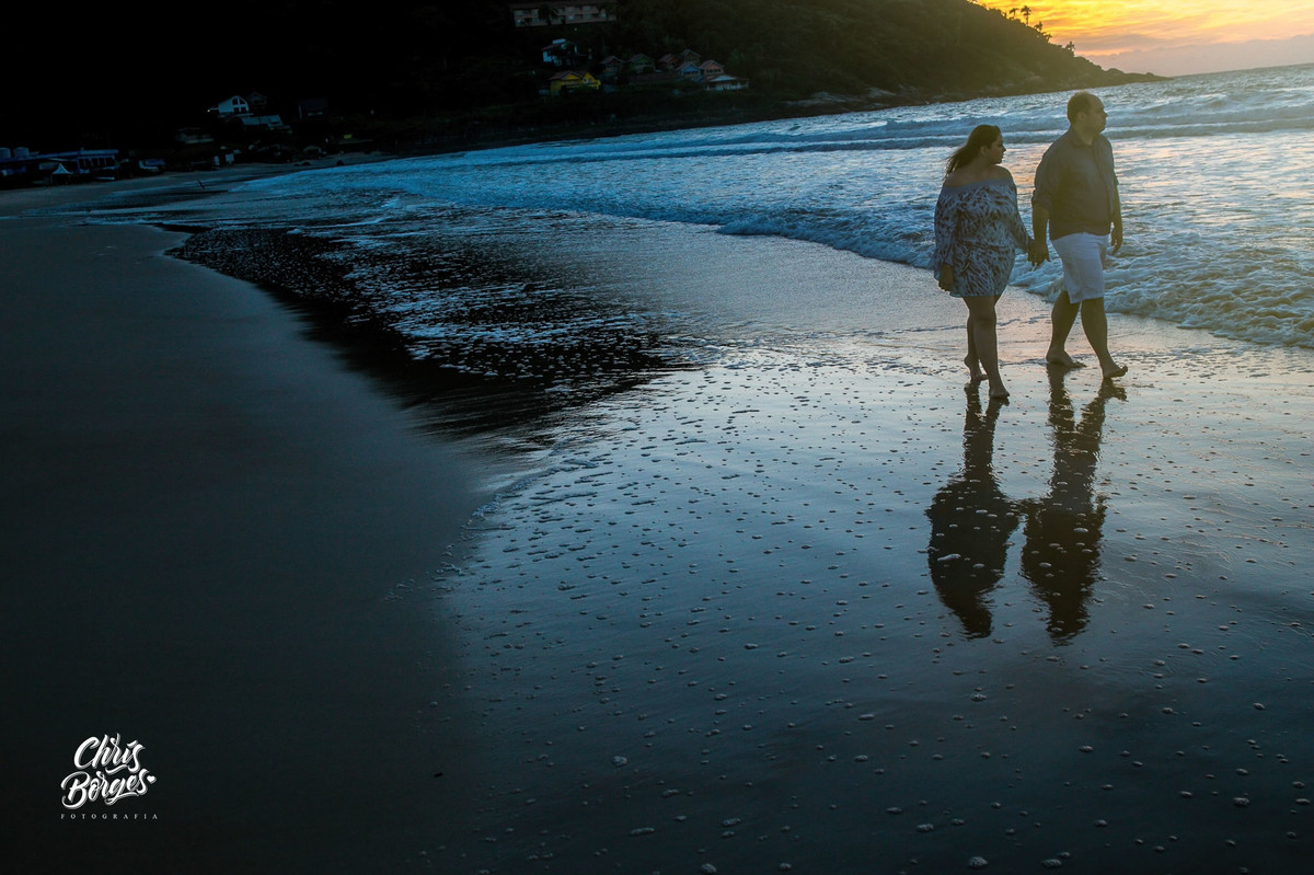 Noivos passeando na praia ao nascer do sol