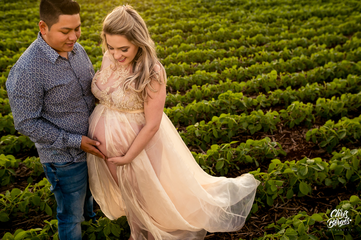 Mamãe e papai acariciando a filha ainda na barriga em meio a plantação de soja