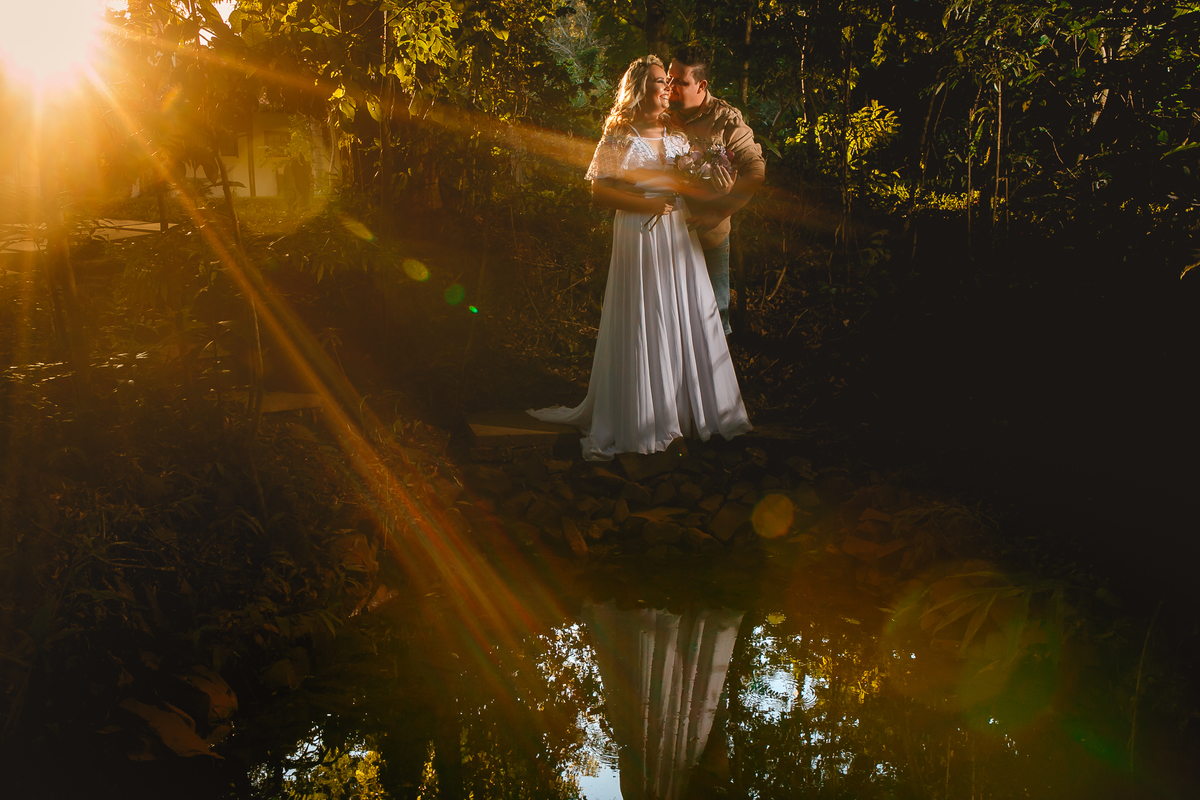 noivos posando para a foto com raios de sol