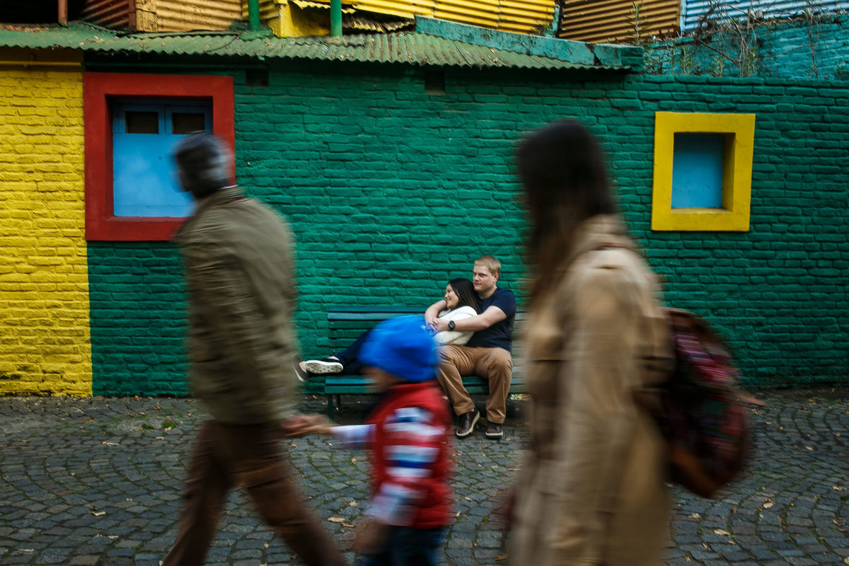 casal abraçado no banco sendo observado por família que passava