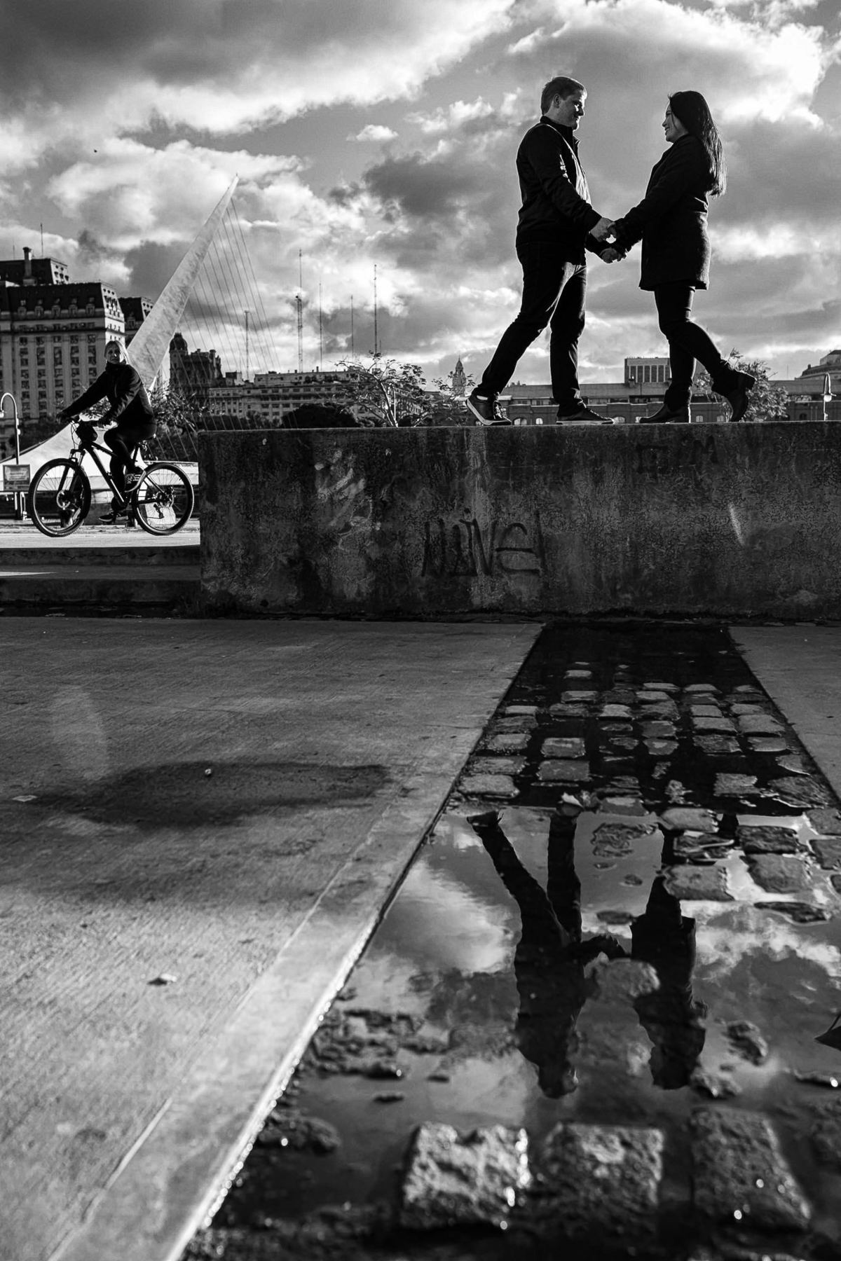 reflexo dos noivos sobre a mureta enquanto são observados por ciclista