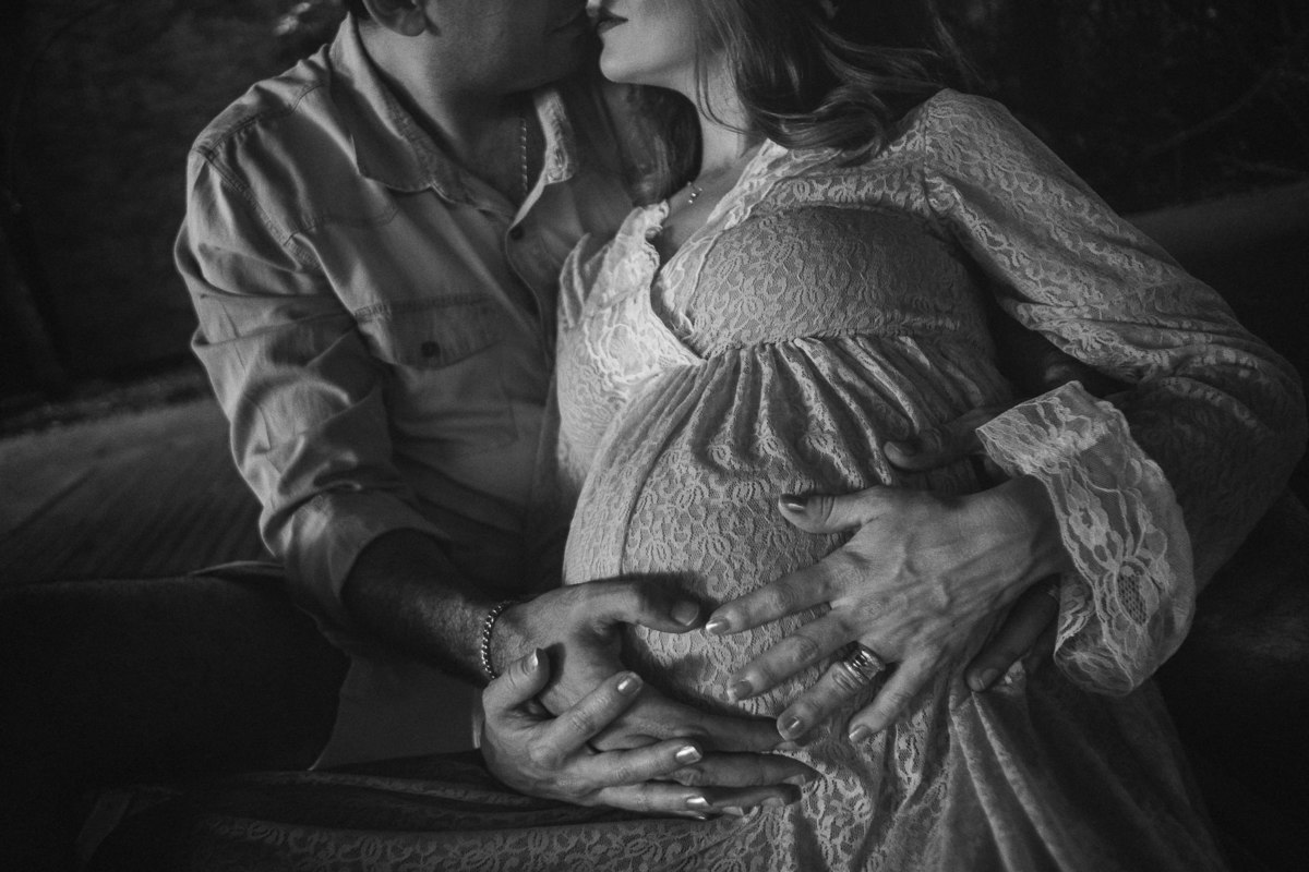 detalhe das mãos do papai e da mamãe gestante protegendo a barriga