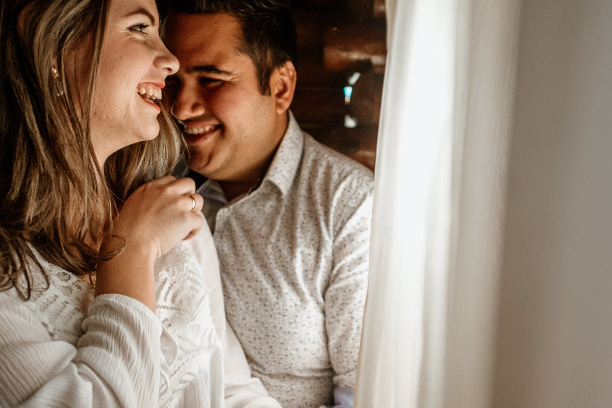noivos sorrindo próximo a janela da cabana itakua