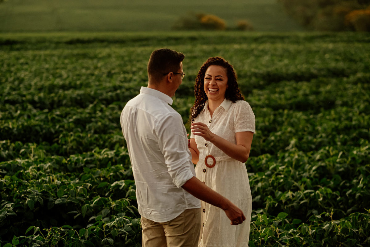 noivos caminhando e sorrindo no meio da lavoura de soja em Medianeira/PR