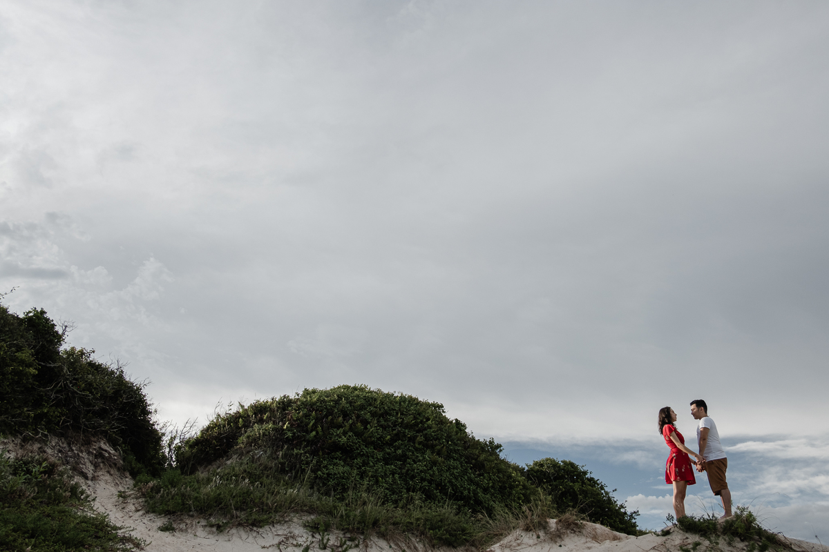 noivos no topo de uma duna na praia no ensaio precasamento