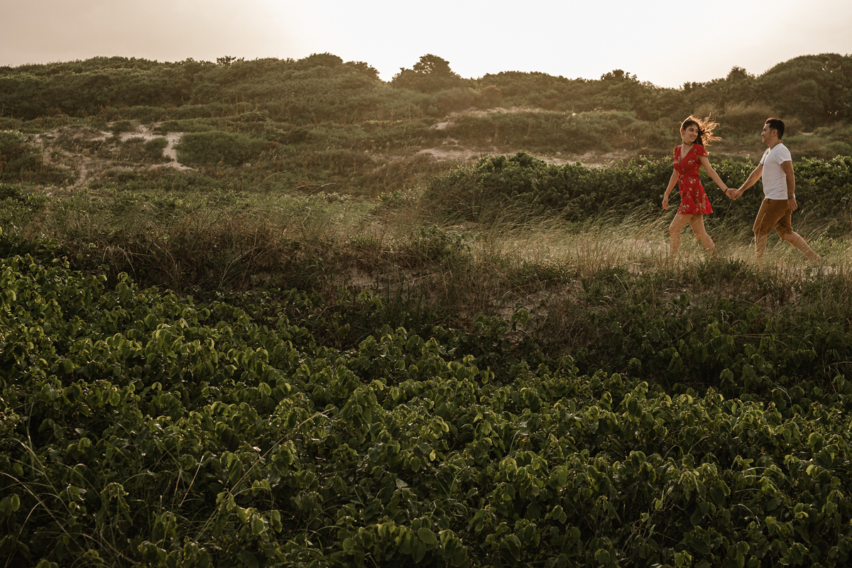 noivos caminhando na areia da praia do campeche em floripa no ensaio pré-casamento