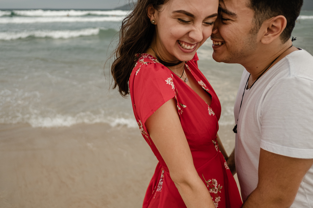 noivos se abraçando e sorridentes na areia da praia do campeche em floripa no ensaio pré-casamento