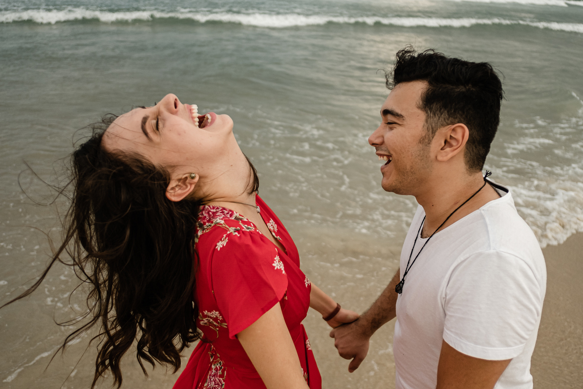 noivos sorridentes na areia da praia do campeche em floripa no ensaio pré-casamento