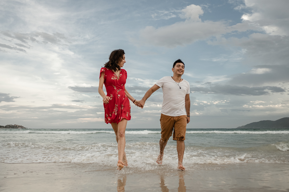 noivos caminhando na areia da praia do campeche em floripa no ensaio pré-casamento