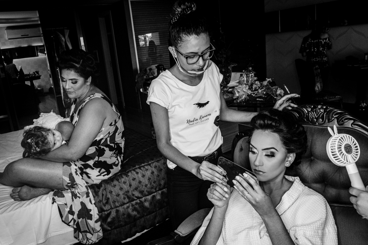noiva verificando sua maquiagem e sendo observada pela daminha no making of