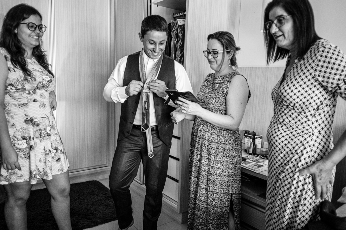 noivo tentando aprender a fazer nó na gravata no making of