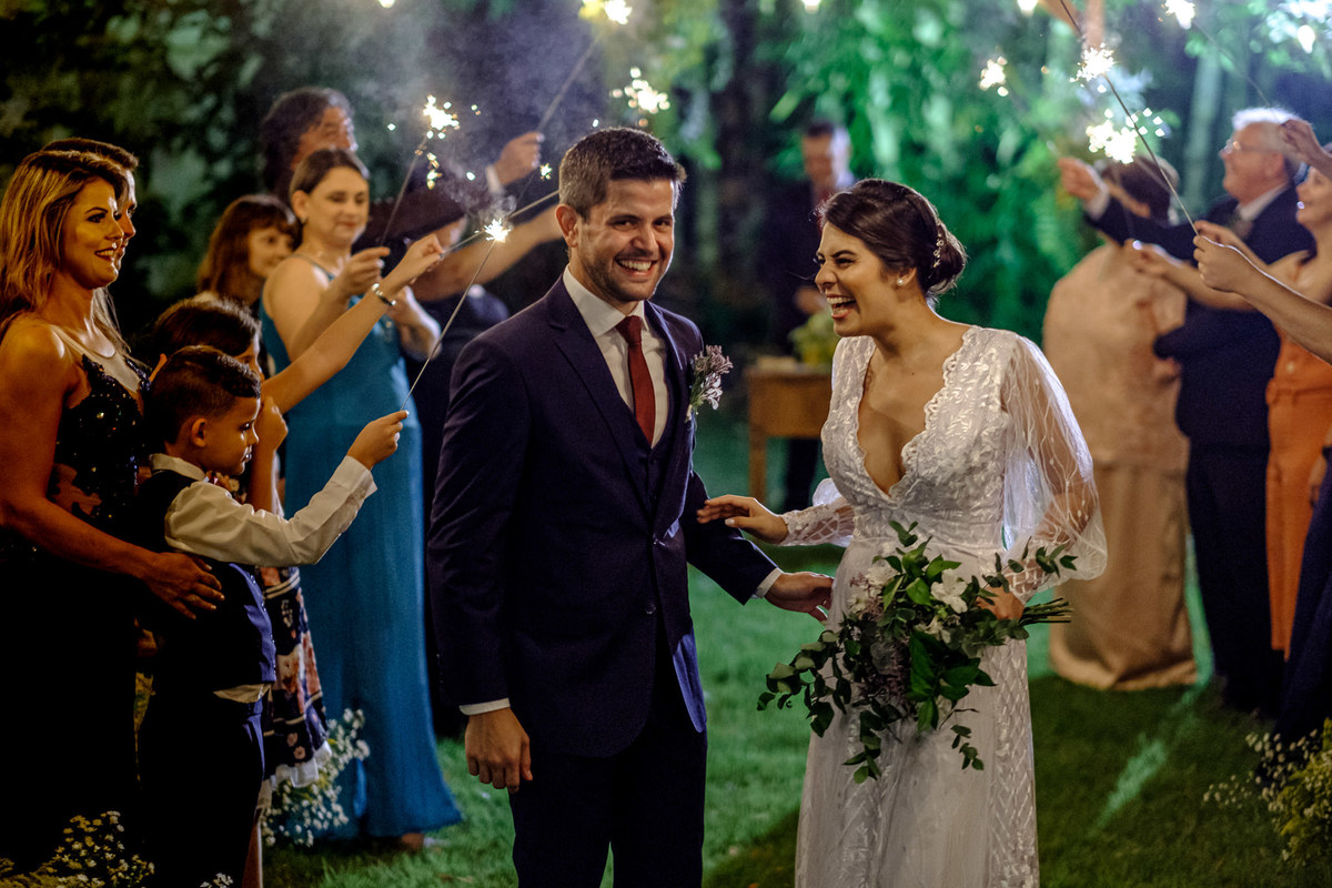 noivos sorrindo em meio aos convidados com sparkles