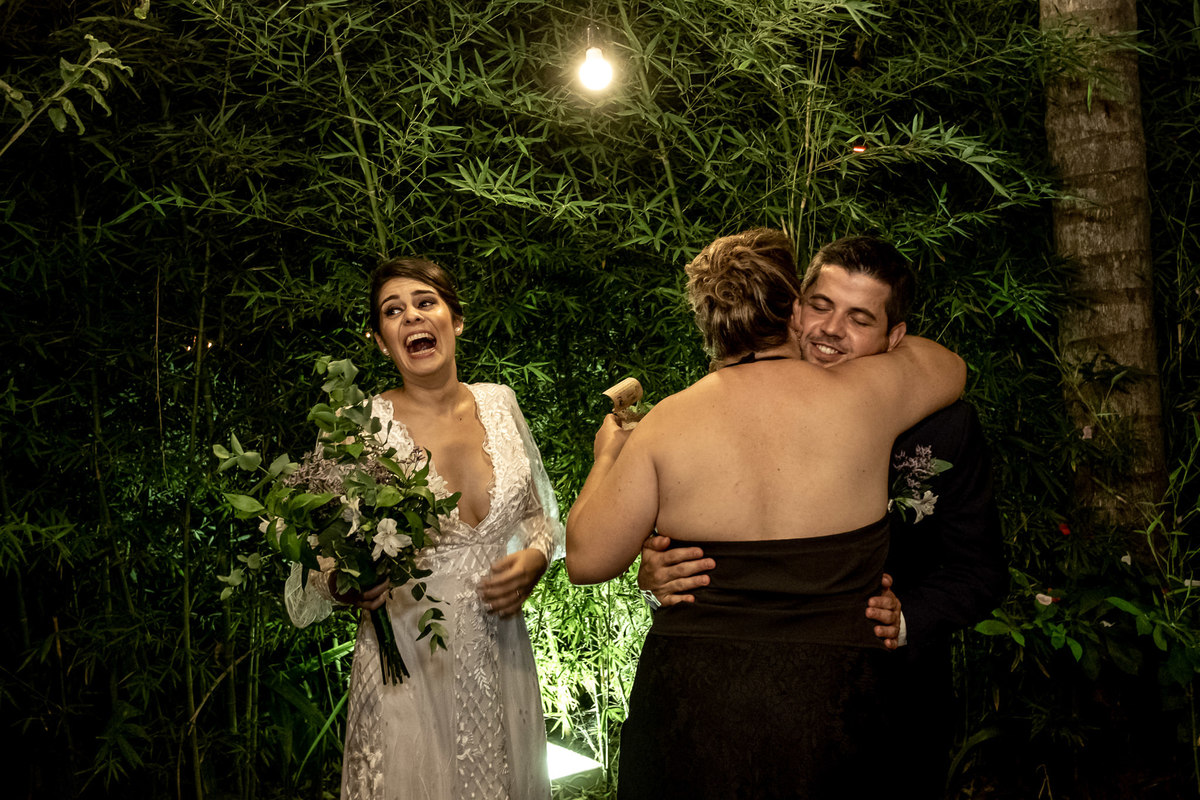 noiva dando gargalhada enquanto o noivo abraça a sogra