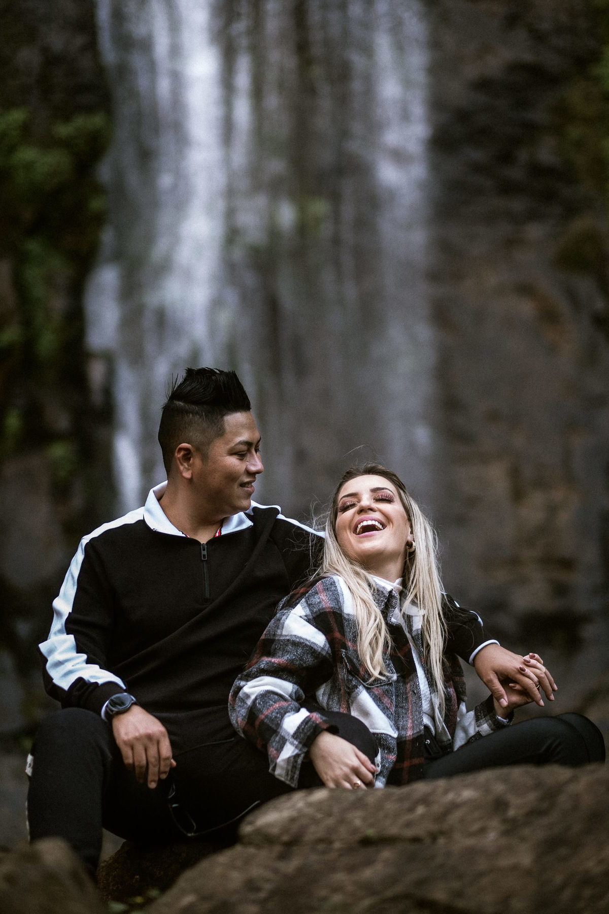 casal sorrindo próximo a cachoeira