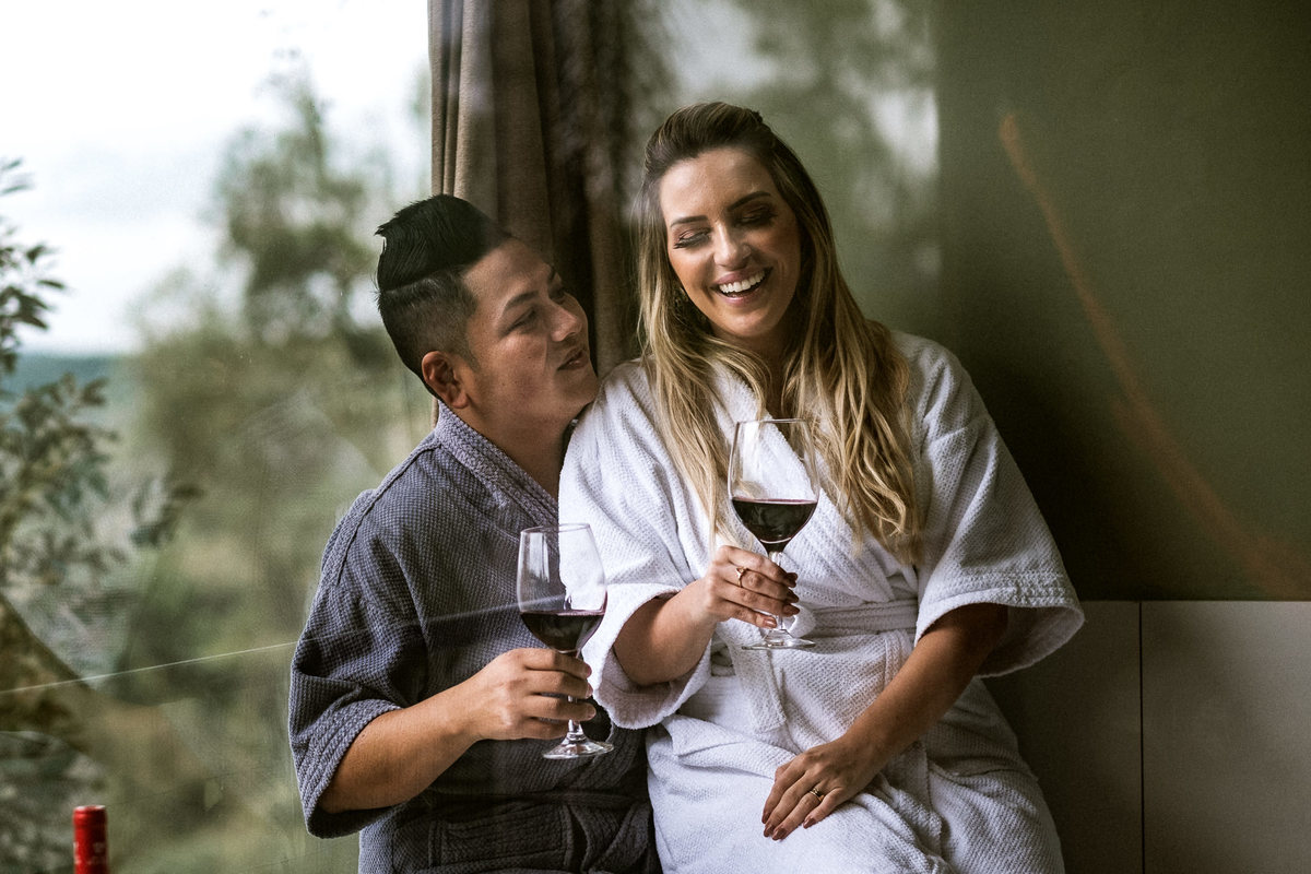 casal sorrindo enquanto bebem vinho na banheira