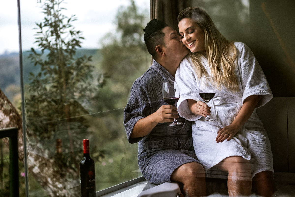 casal sorrindo enquanto bebem vinho na banheira