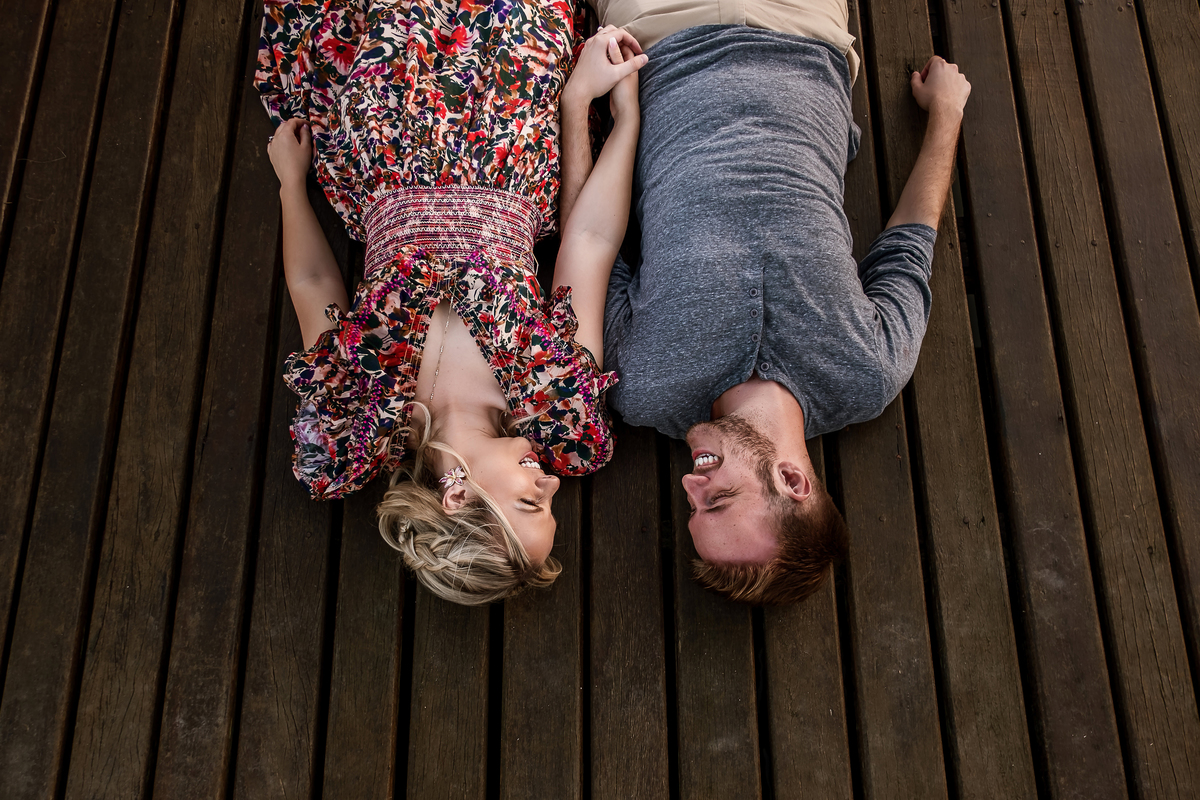 casal sorridente deitado no deck