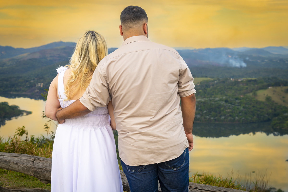No alto do Morro do Capuava, Kamila e Daniel contemplam o amor que os eleva — tão leve quanto o voo ao fundo., ensaio pré-wedding Alphaville, ensaio fotográfico pré-wedding Morro do Capuava ensaio, fotos de casal ao pôr do sol, pré-wedding com parapente