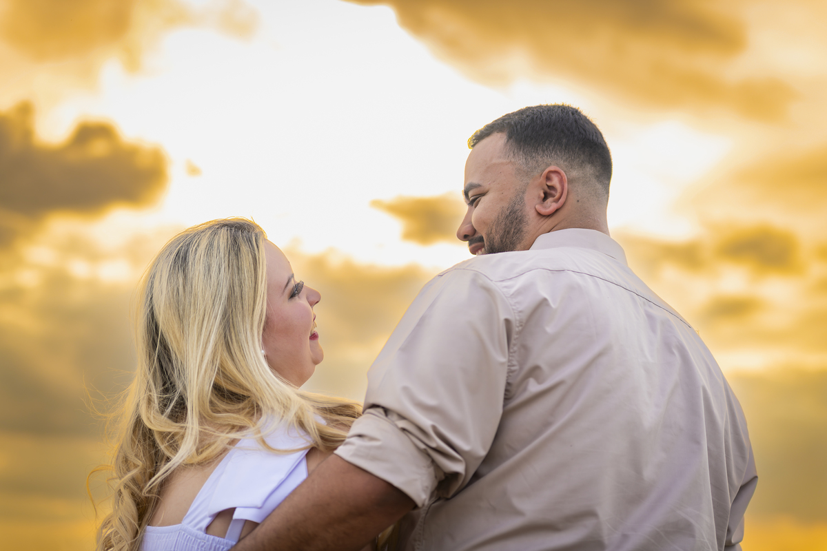 No alto do Morro do Capuava, Kamila e Daniel contemplam o amor que os eleva — tão leve quanto o voo ao fundo., ensaio pré-wedding Alphaville, ensaio fotográfico pré-wedding Morro do Capuava ensaio, fotos de casal ao pôr do sol, pré-wedding com parapente