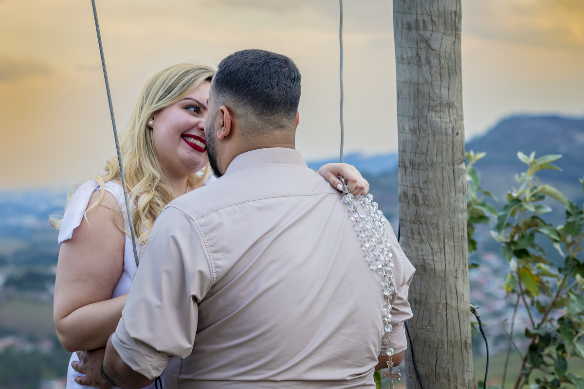 No alto do Morro do Capuava, Kamila e Daniel contemplam o amor que os eleva — tão leve quanto o voo ao fundo., ensaio pré-wedding Alphaville, ensaio fotográfico pré-wedding Morro do Capuava ensaio, fotos de casal ao pôr do sol, pré-wedding com parapente