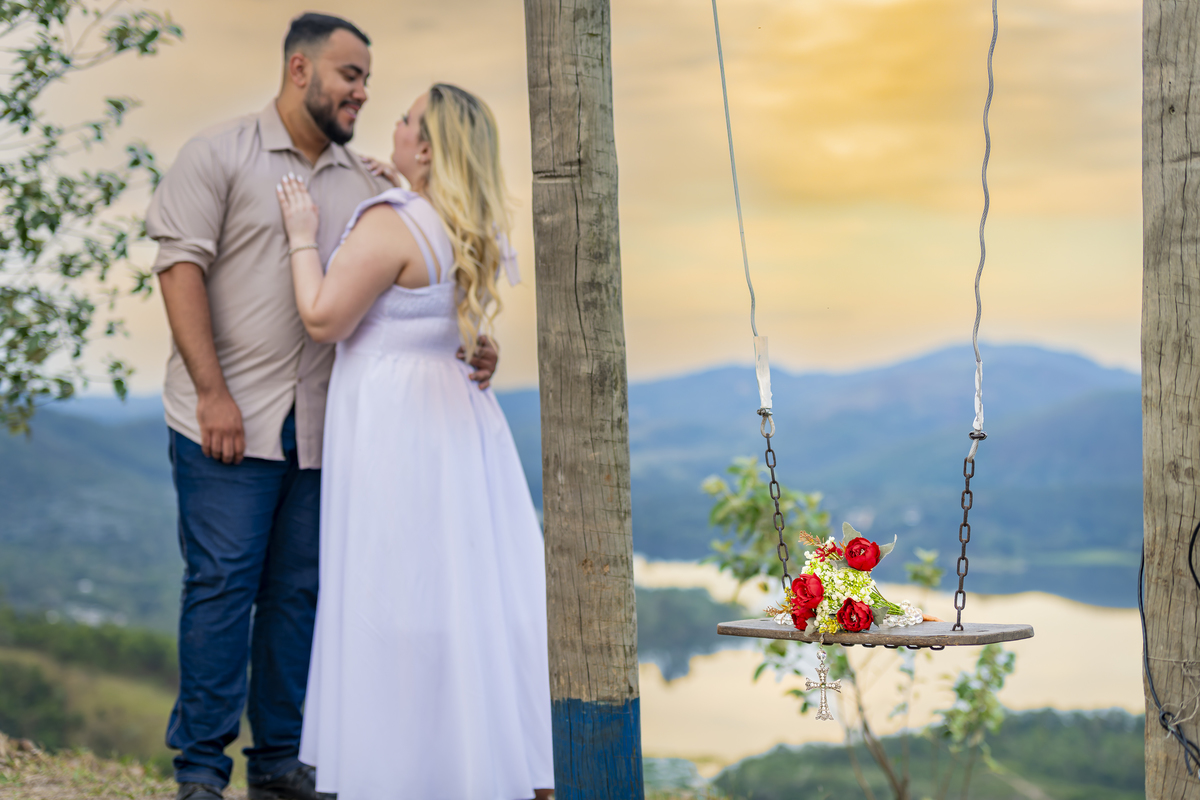 No alto do Morro do Capuava, Kamila e Daniel contemplam o amor que os eleva — tão leve quanto o voo ao fundo., ensaio pré-wedding Alphaville, ensaio fotográfico pré-wedding Morro do Capuava ensaio, fotos de casal ao pôr do sol, pré-wedding com parapente