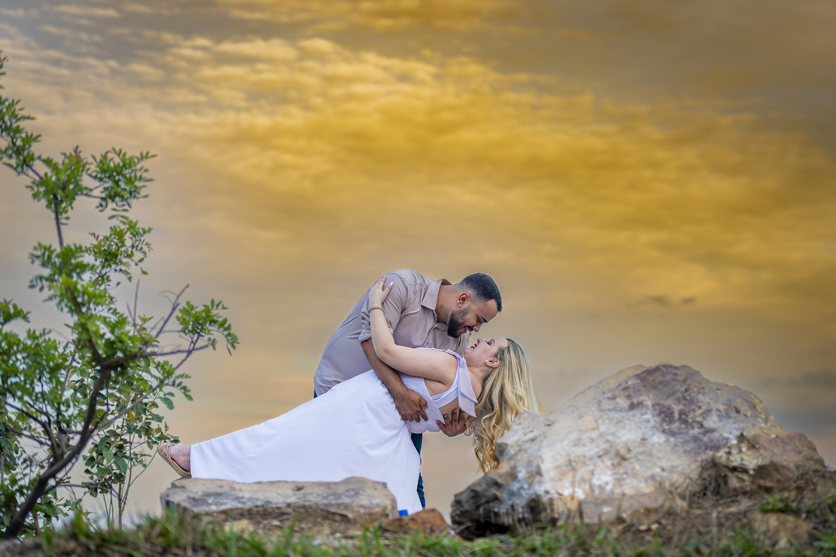 No alto do Morro do Capuava, Kamila e Daniel contemplam o amor que os eleva — tão leve quanto o voo ao fundo., ensaio pré-wedding Alphaville, ensaio fotográfico pré-wedding Morro do Capuava ensaio, fotos de casal ao pôr do sol, pré-wedding com parapente