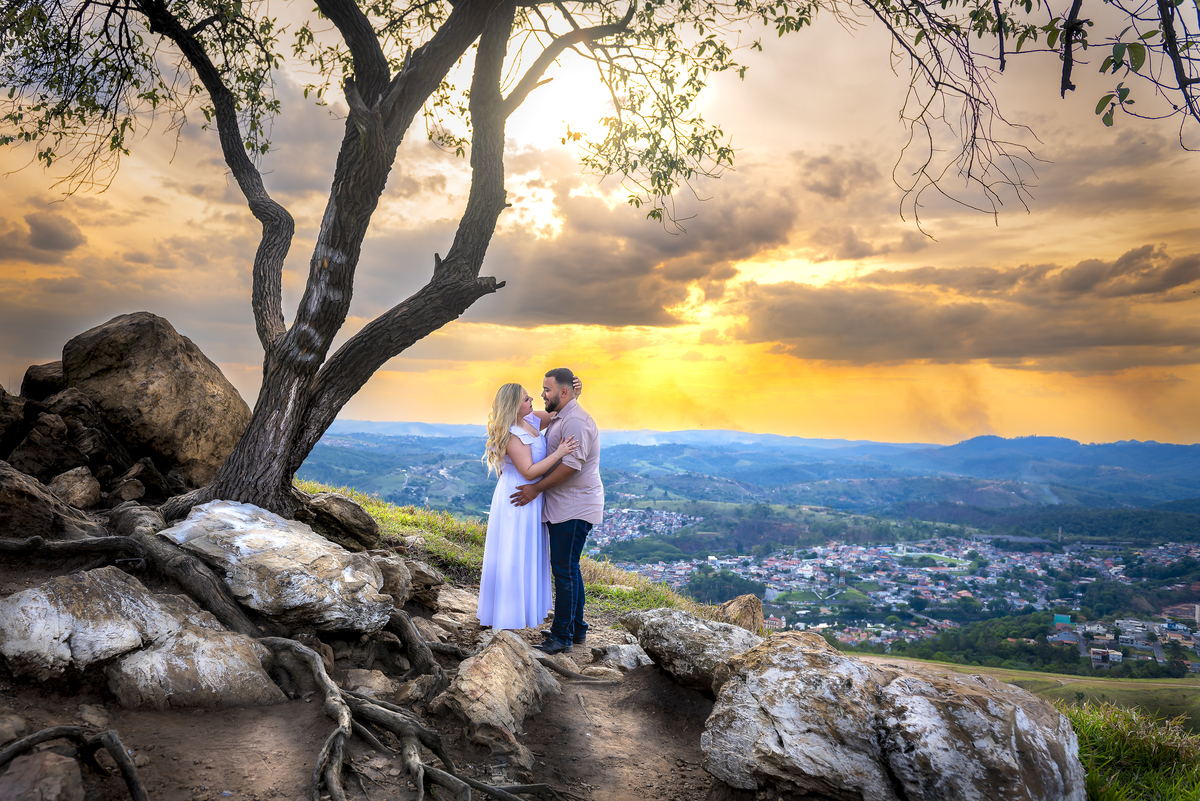 No alto do Morro do Capuava, Kamila e Daniel contemplam o amor que os eleva — tão leve quanto o voo ao fundo., ensaio pré-wedding Alphaville, ensaio fotográfico pré-wedding Morro do Capuava ensaio, fotos de casal ao pôr do sol, pré-wedding com parapente