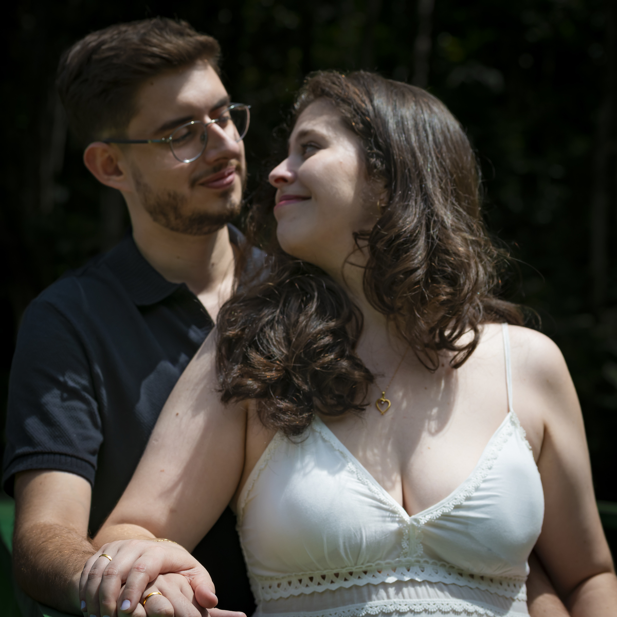 Retrato em luz e sombra contrastante do casal, Noiva apoiada no ombro de Noivo com colar de coração em destaque, Jardim Botânico de São Paulo.