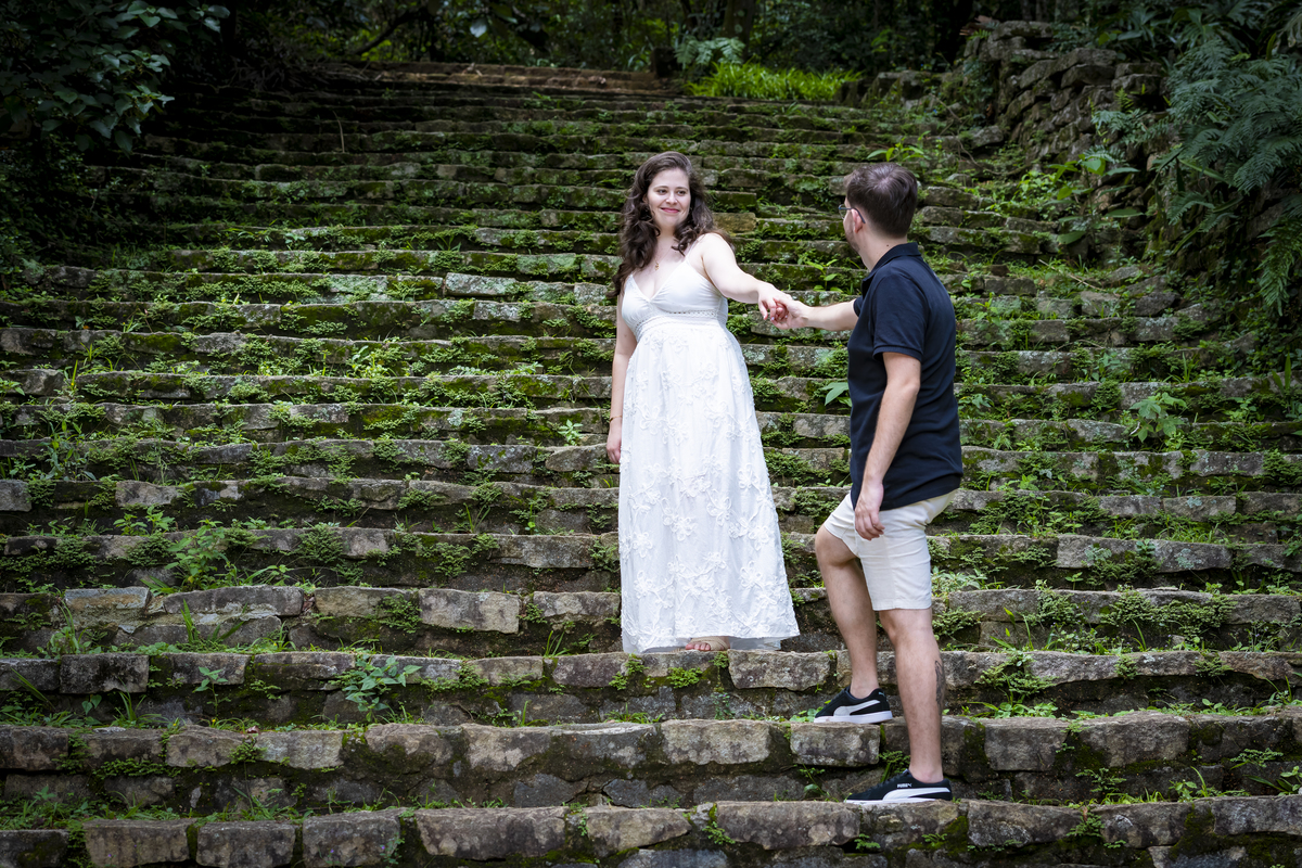 Noiva estende a mão para Noivo na escadaria histórica de pedra, ensaio pré-wedding no Jardim Botânico de São Paulo.